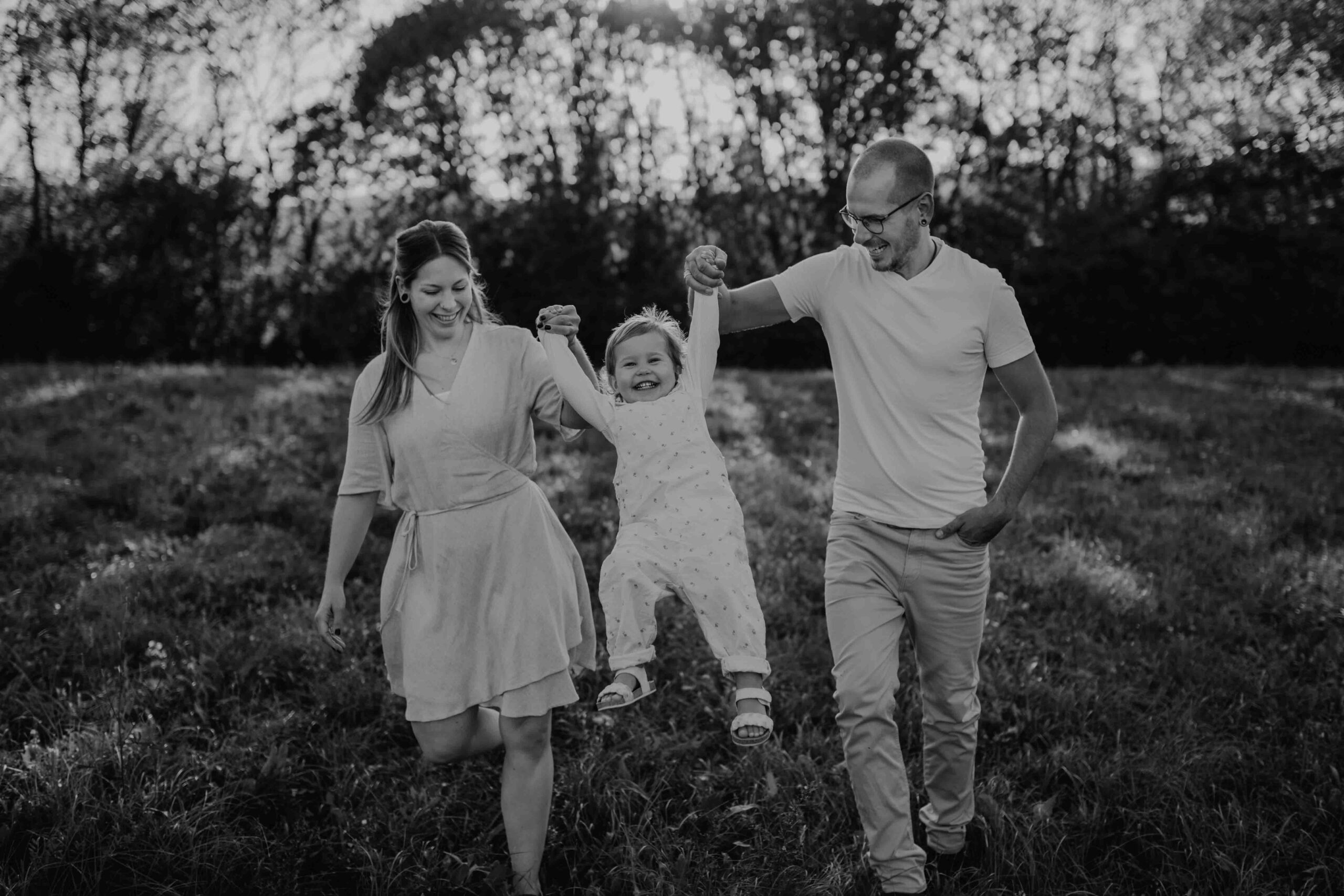 Mama und Papa schwingen ihre Tochter bei dem Fotoshooting in die Luft