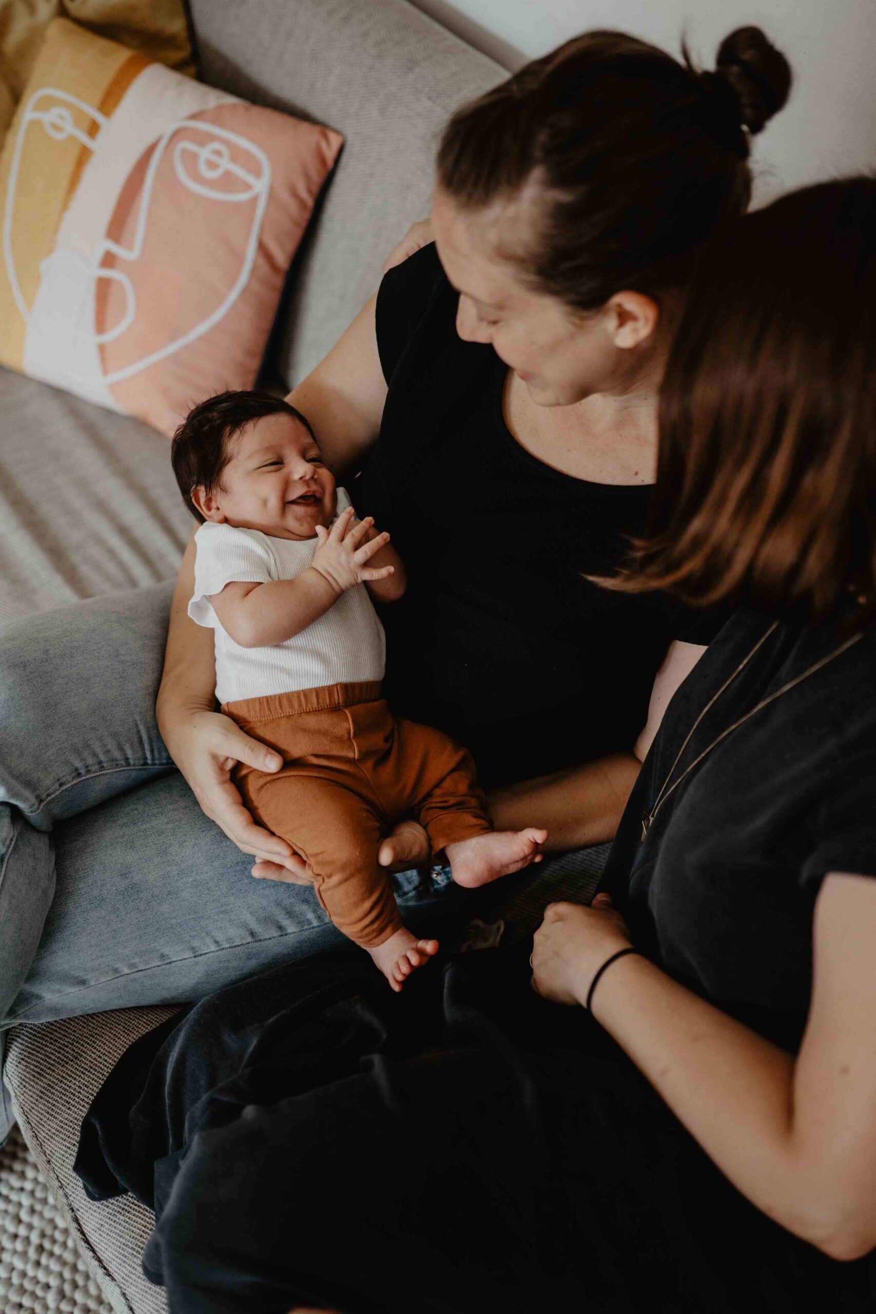 Eine der Mamas hält ihr Baby in den Armen, das Baby lacht breit.