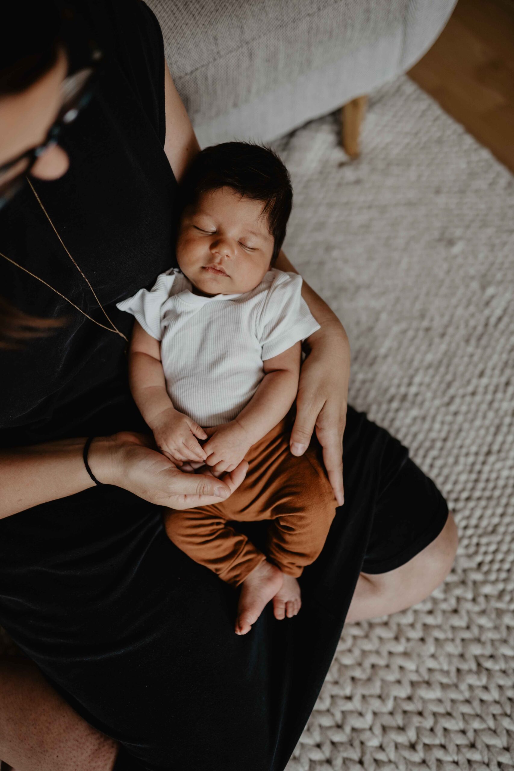 Natürliche Babyfotos in Mödling, Moritz liegt in den Armen seiner Mama und schläft ganz entspannt.