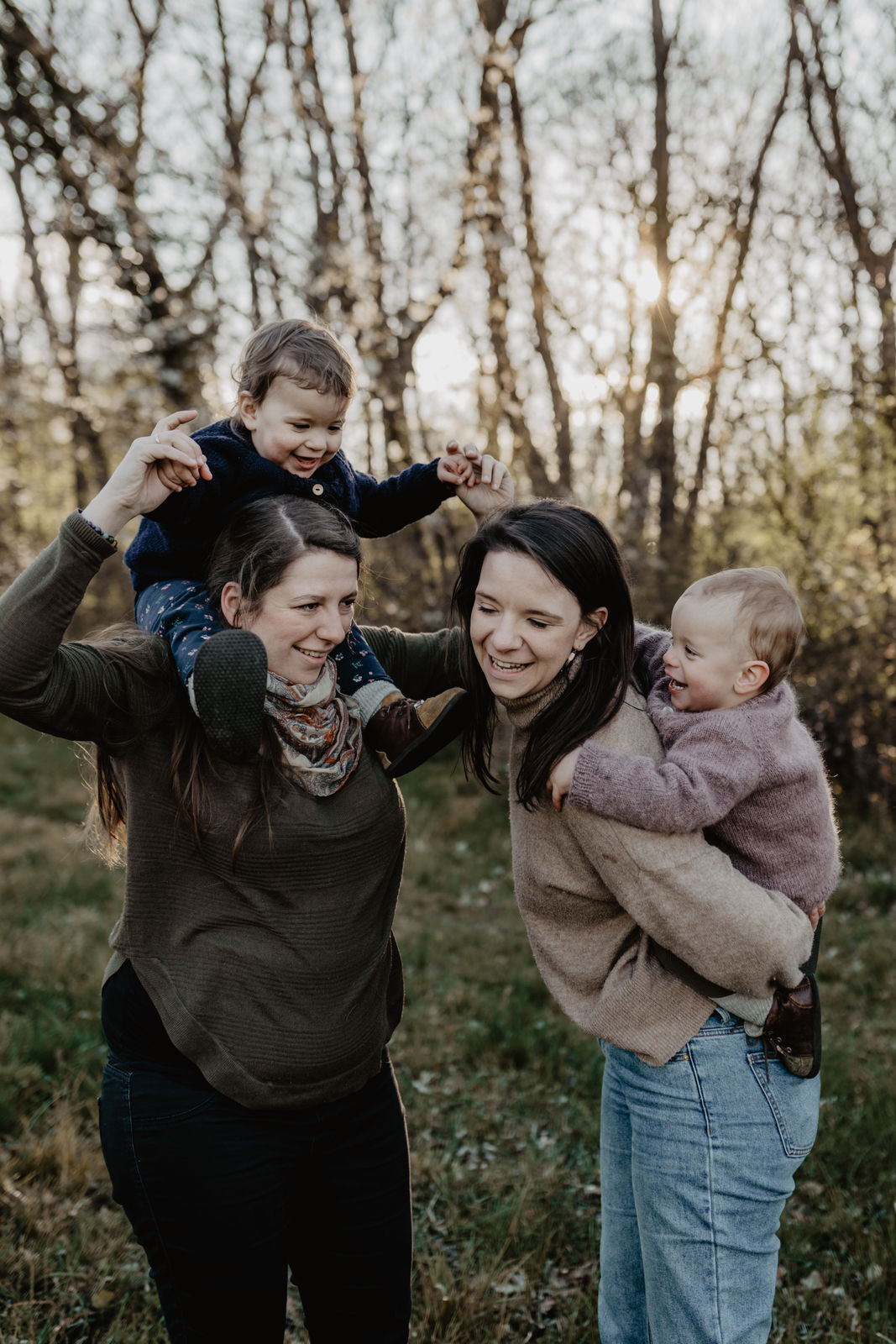 2 Mamas tragen ihre Kinder Huckepack und auf den Schultern, während wir Familienfotos in Niederösterreich schaffen. Alle wirken glücklich und lachen